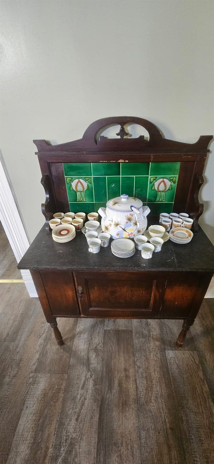 An antique secretary cabinet displaying china teacups and saucers.