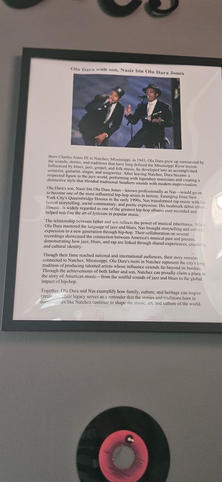 A framed feature article and a vinyl record displayed as part of an exhibit.