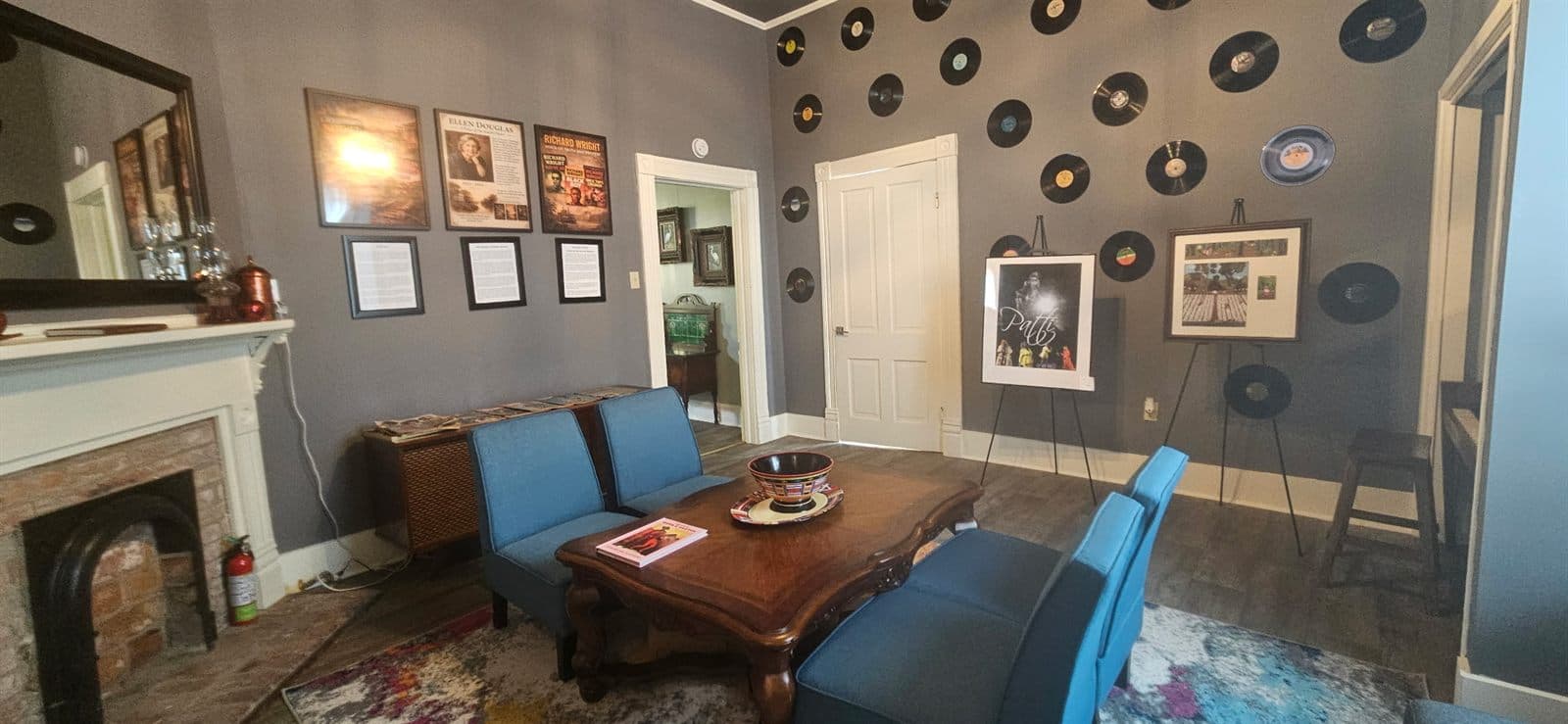 Wide view of the music room with a fireplace, framed photographs, and a record-lined wall.