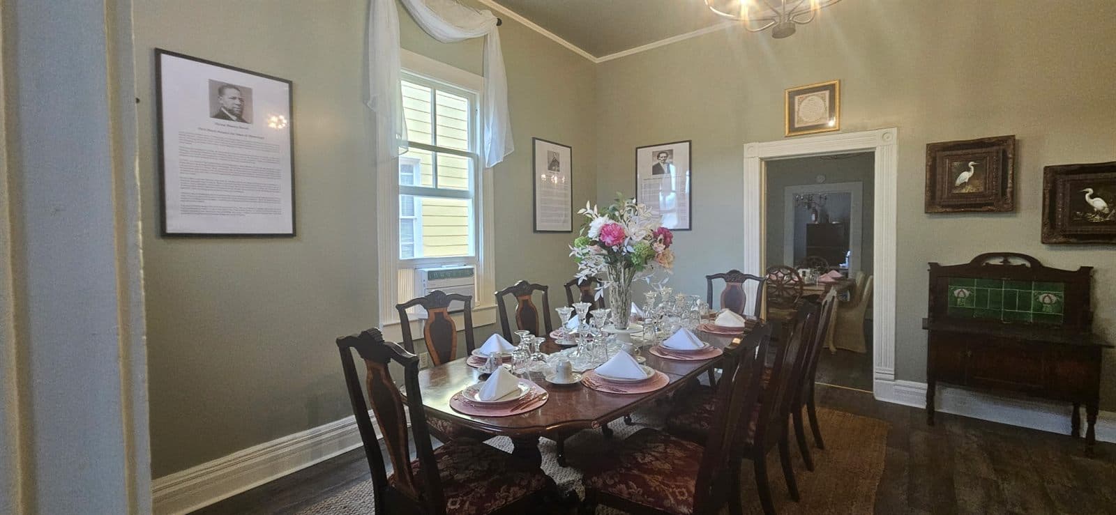 A dining table set with linens, place settings, and floral centerpieces for guests.