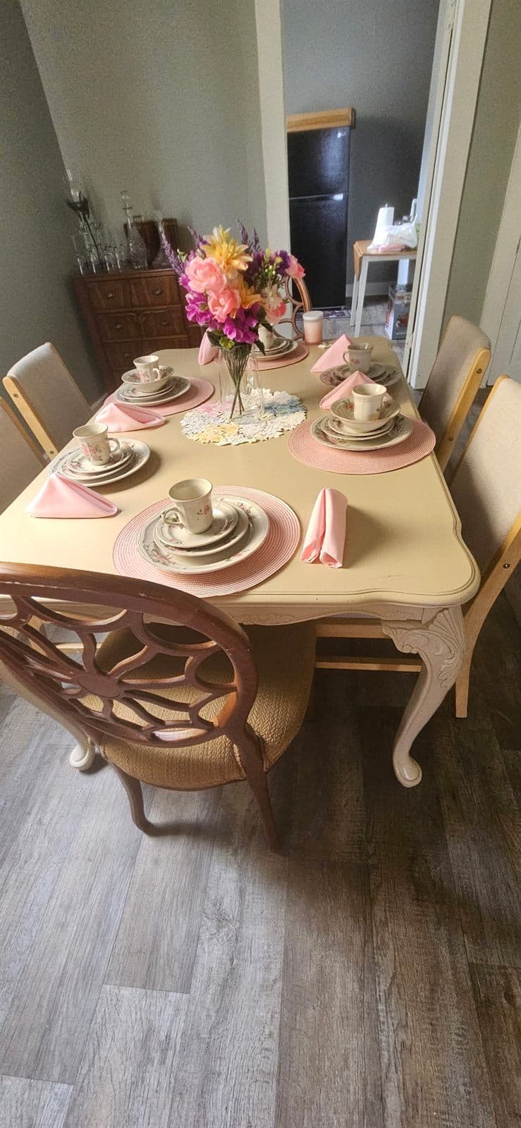A small table set for tea with fresh pink flowers, ready for conversation.