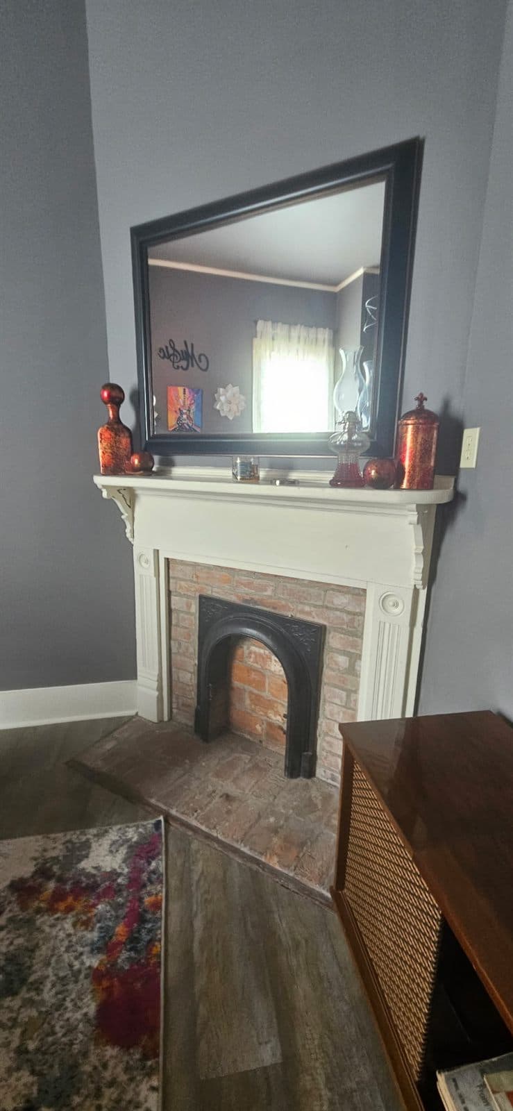 Detail of a fireplace mantel with a mirror and small keepsakes.