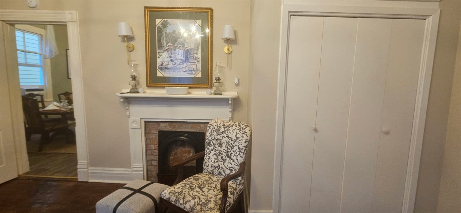 A historic interior room with a fireplace, framed pictures, and a cushioned bench.
