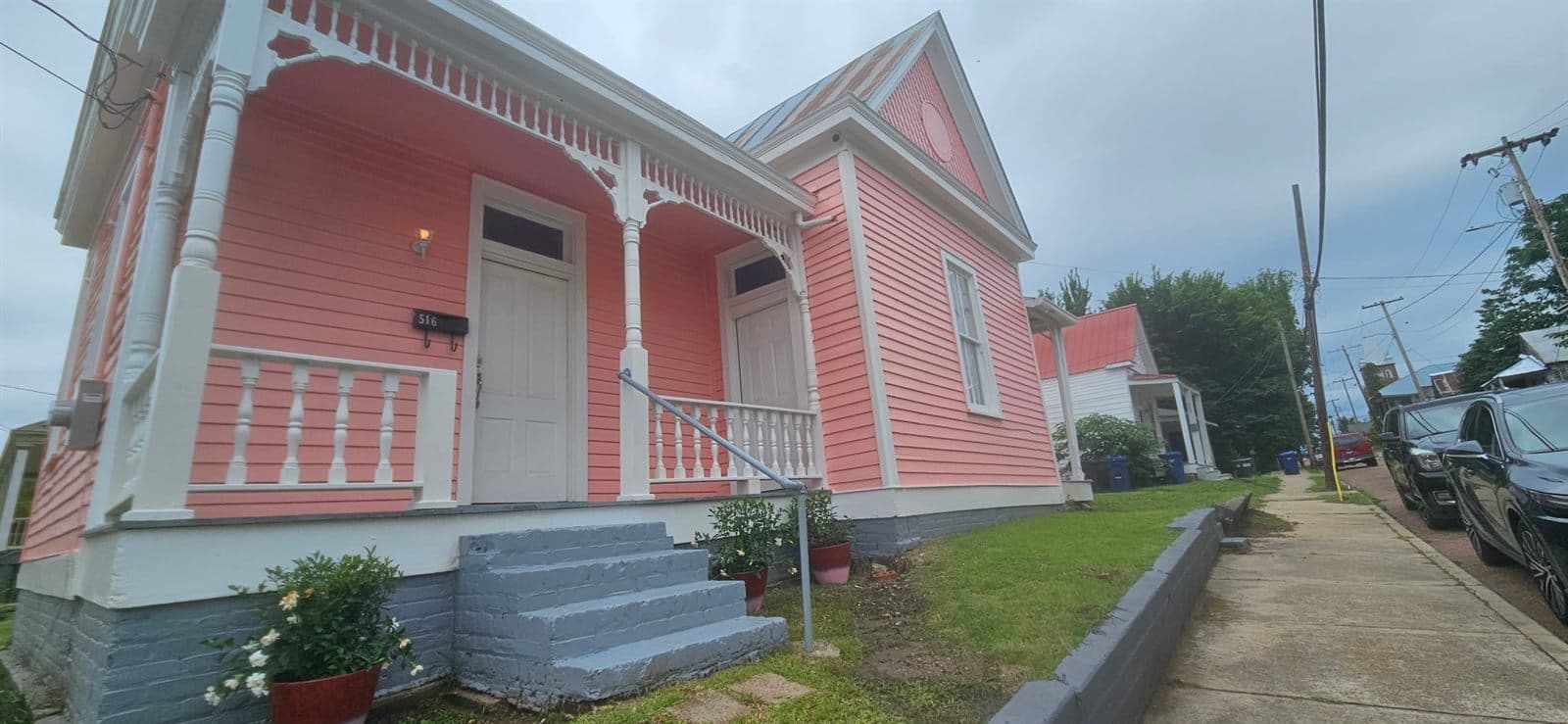 The Legacy at Madison — a historic coral-pink cottage in Natchez, Mississippi, with white trim and a raised front porch.